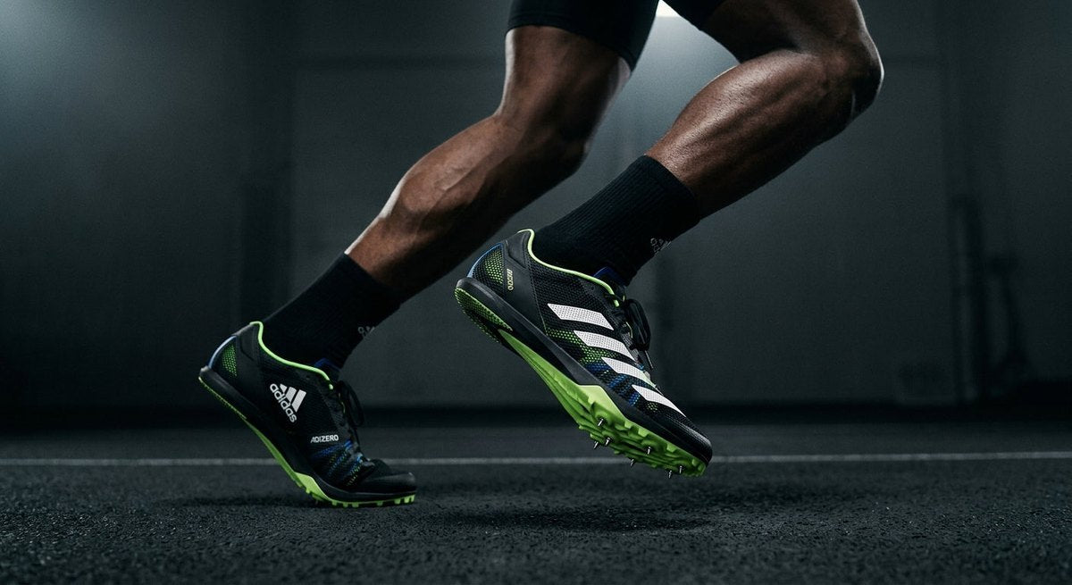 A side-profile studio render of the Adidas Adizero Finesse highlighting the aggressive spike plate geometry and mesh material construction.