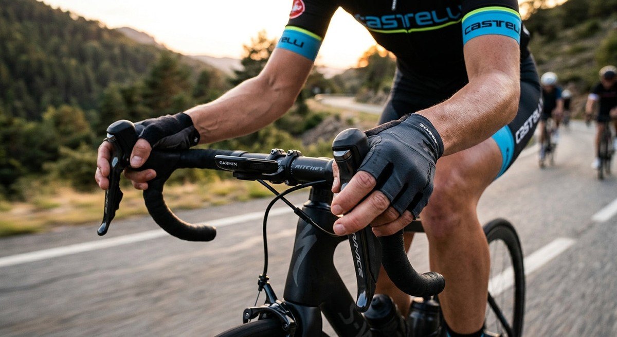 Action shot of a cyclist's hands on the hoods of a modern electronic groupset during a fast-paced training ride