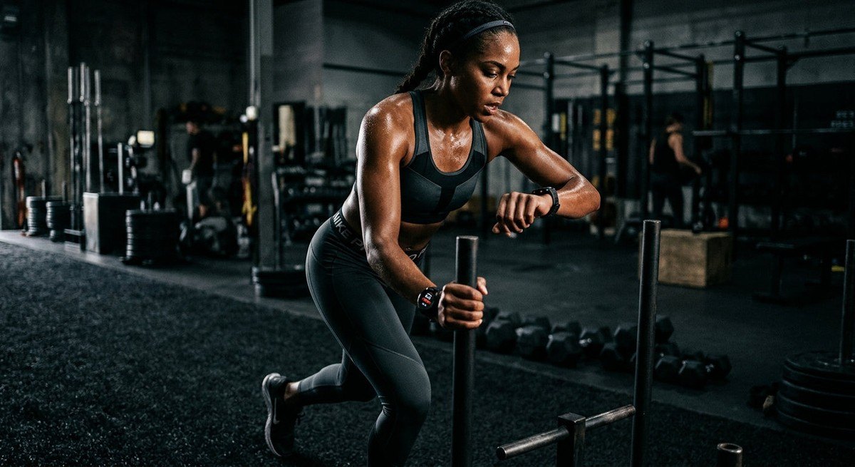 An athlete monitoring their heart rate on a sleek wearable device during a high-intensity training session in a moody, professional environment