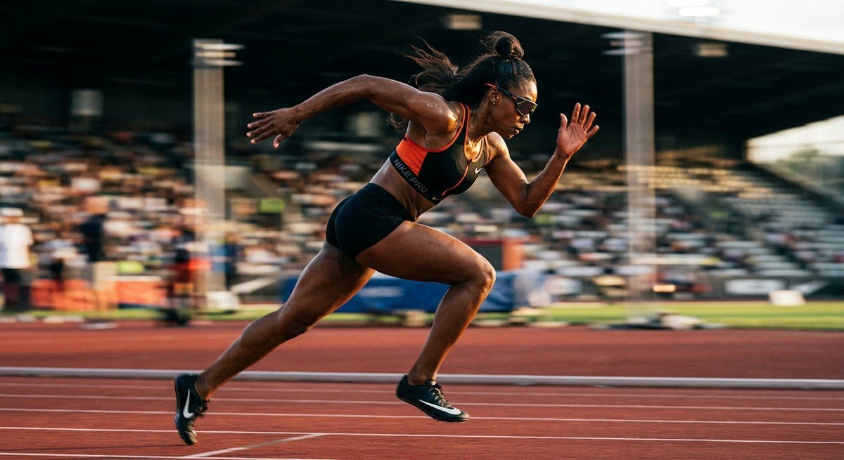An athlete sprinting with motion blur in the background, focusing on the aerodynamic profile of the Nike Vision Flyfree eyewear in a high-speed sports photography style.
