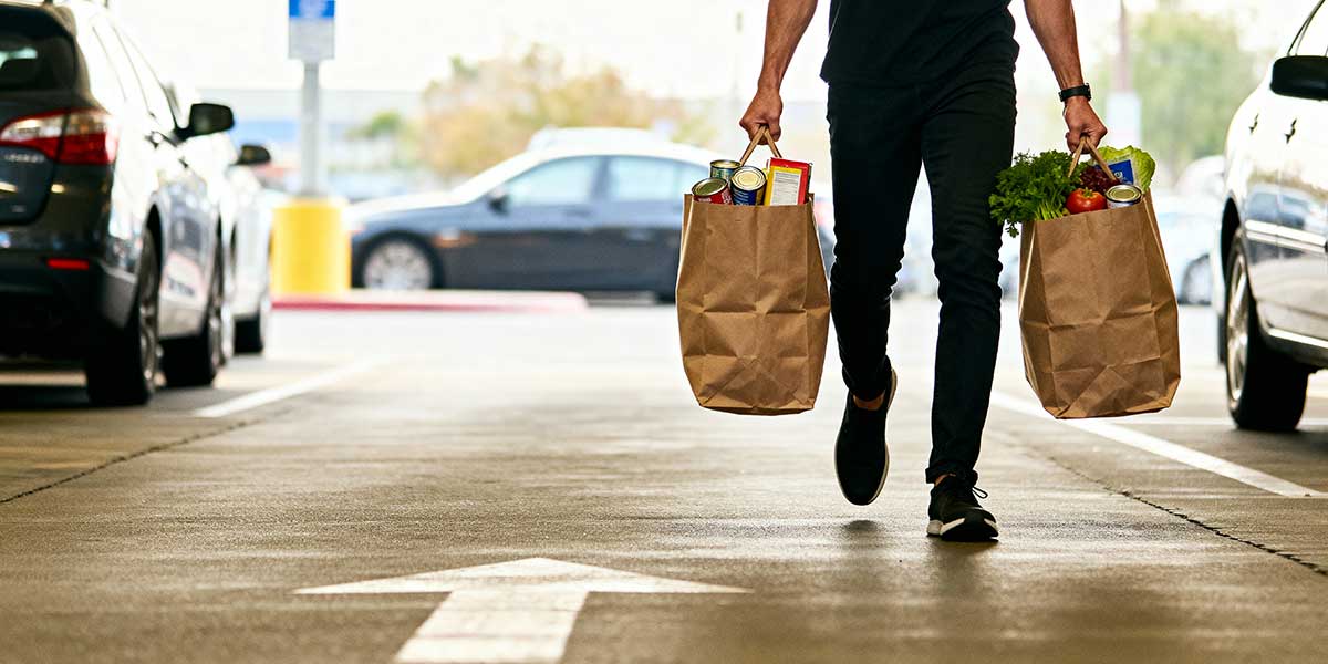Fit person carrying heavy shopping bags by hand to burn extra calories instead of using a trolley.