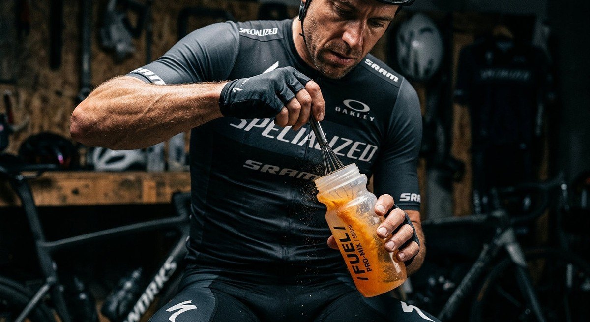 Cinematic close-up of a high-performance cycling drink mix powder being stirred into a bottle with dramatic studio lighting and sharp texture details.