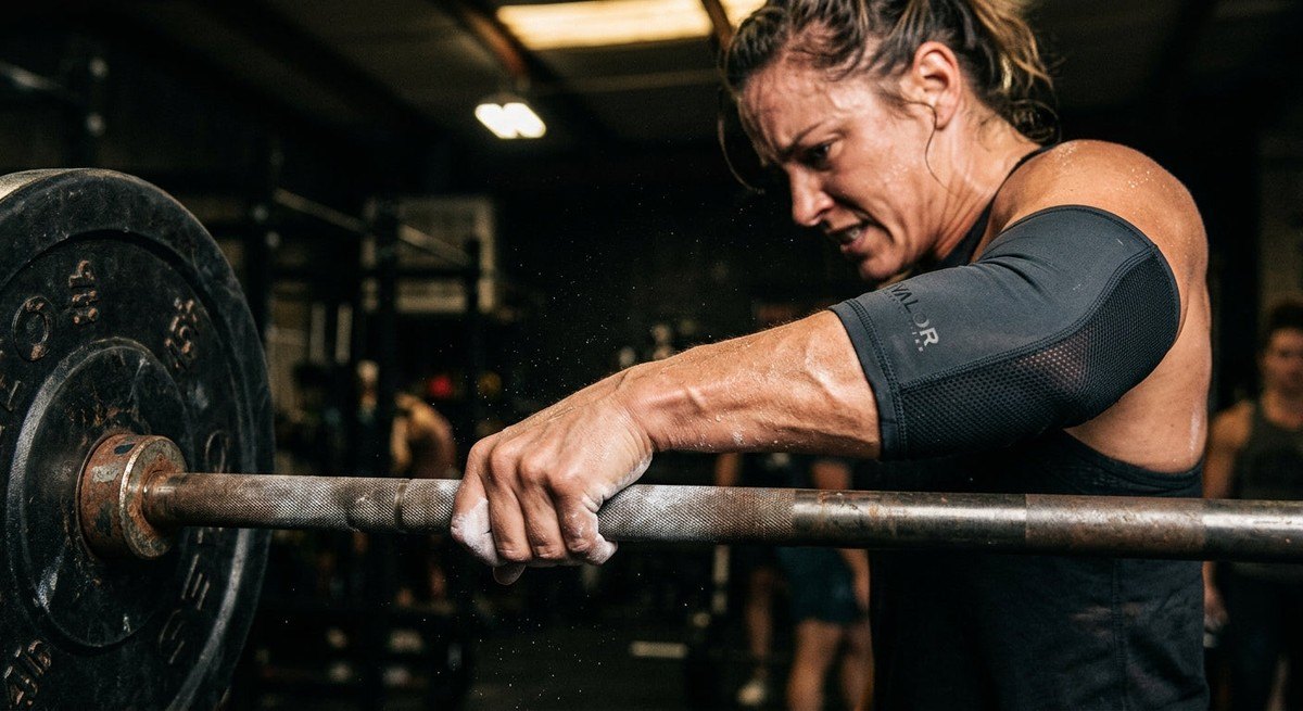 Close-up high-speed photograph of a determined athlete gripping a heavy steel handle with visible muscle tension and sweat.