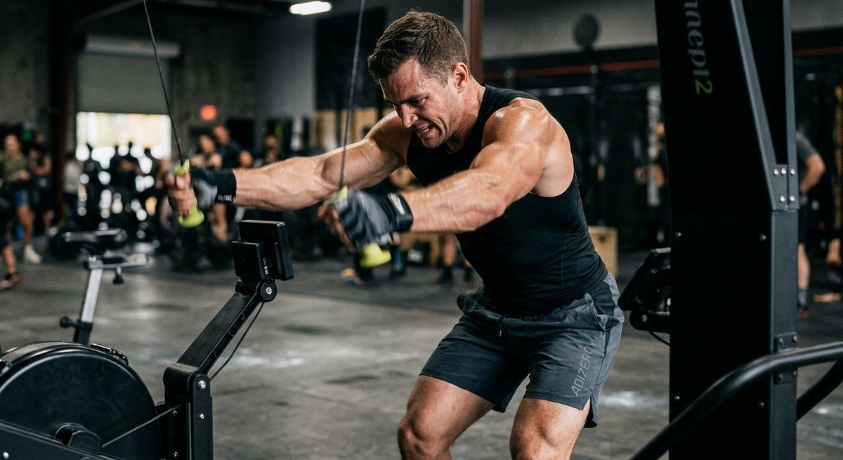 Close-up of a competitive athlete using a SkiErg with perfect form, showing intense focus, muscle definition, and motion blur on the handles.