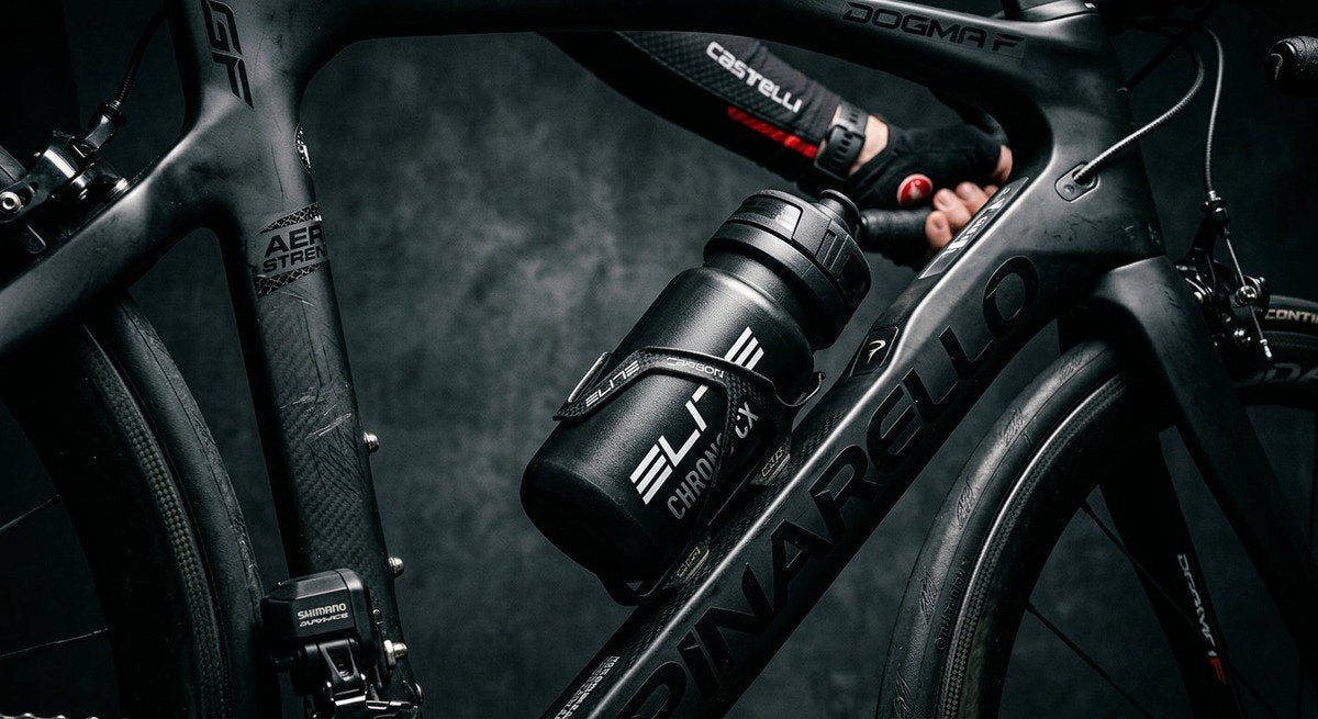 Close-up of a high-performance aero bidon mounted on a carbon fibre frame, showcasing textured materials and professional racing equipment in a moody, high-contrast studio setting.