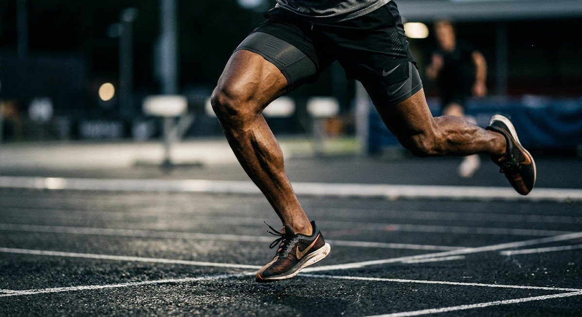 Close-up of a high-performance athlete's legs in motion with sharp focus on muscle texture and dramatic shadow contrast