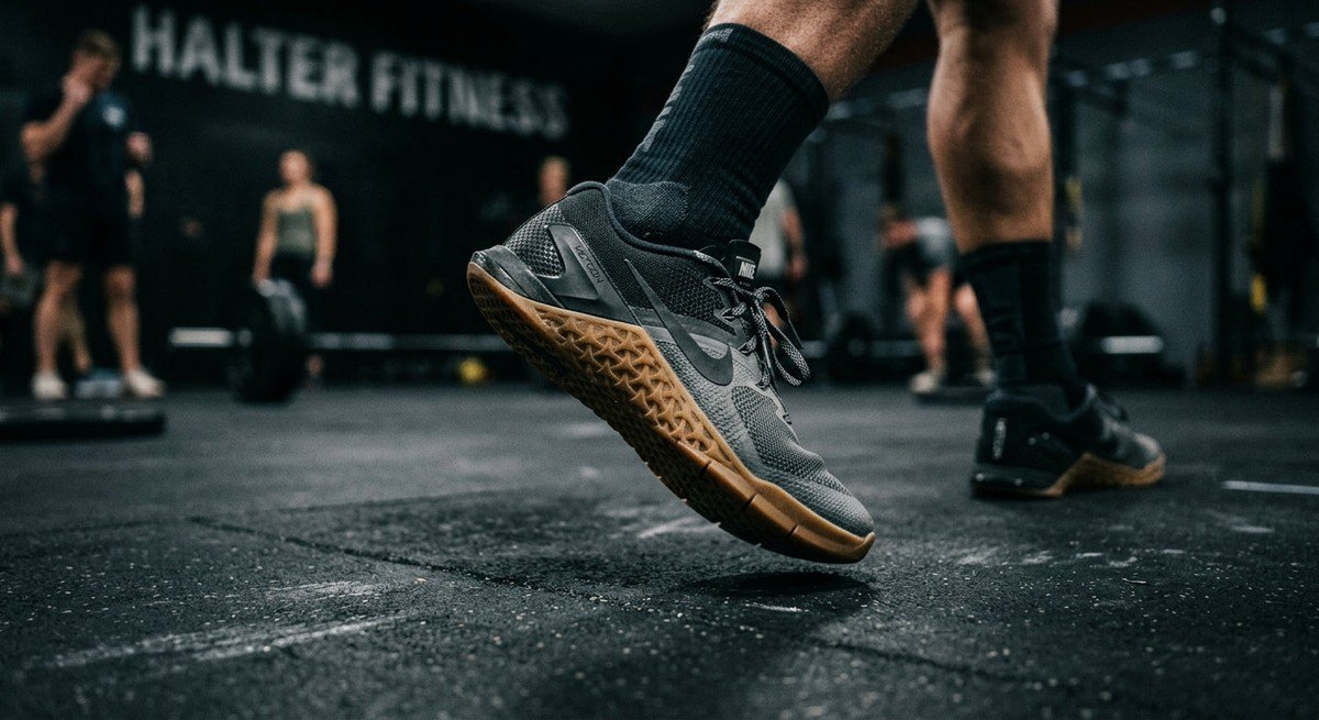 Close-up of a high-performance training shoe mid-stride on a gym floor, capturing sharp textures and motion blur with a moody, high-contrast aesthetic.