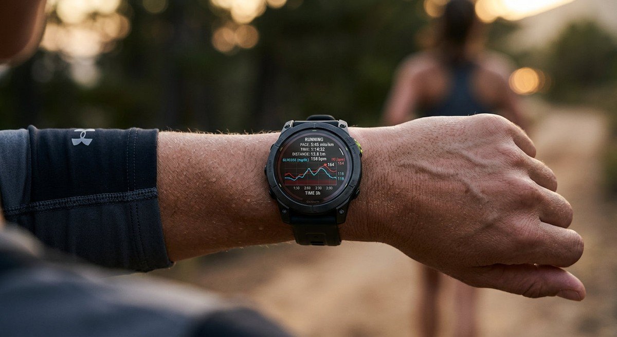 Close-up of a high-tech sports watch display showing real-time glucose graphs overlaid with heart rate data