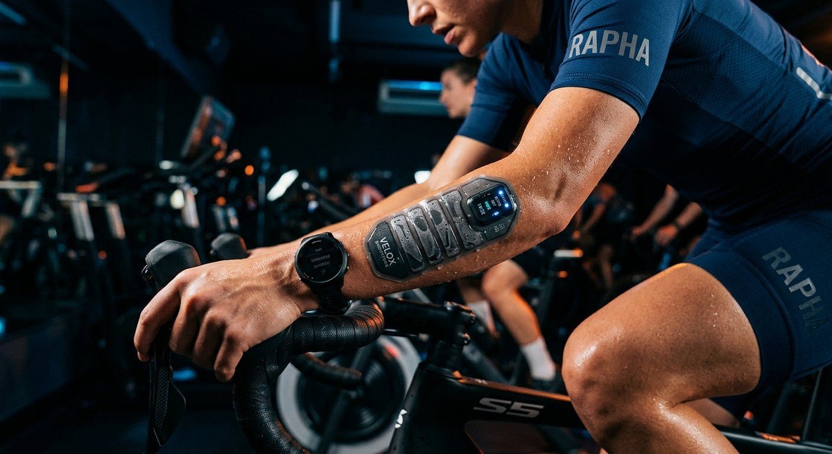 Close-up of a high-tech sweat collection patch on an athlete's forearm during a intense cycling session.