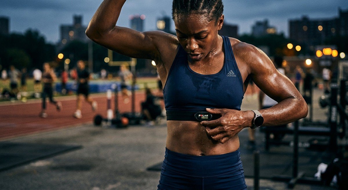 Close-up of a professional athlete checking a high-precision heart rate monitor strap during a vigorous training session.