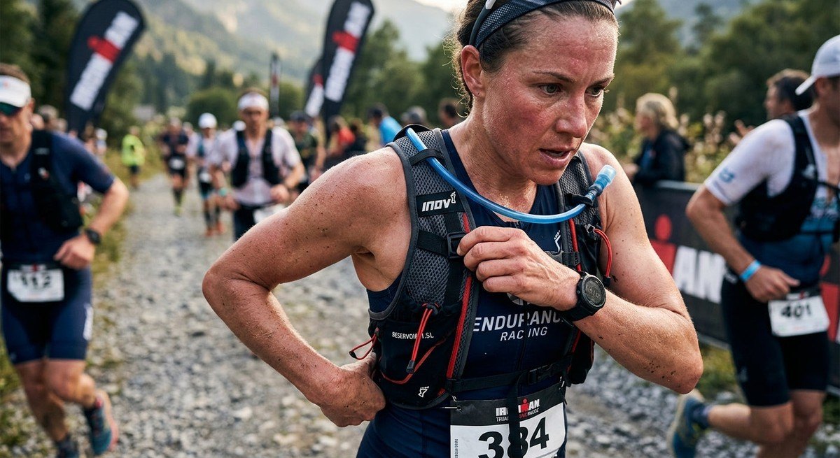Close-up of a triathlete adjusting a high-capacity hydration vest during a race, featuring sharp details and realistic skin textures.