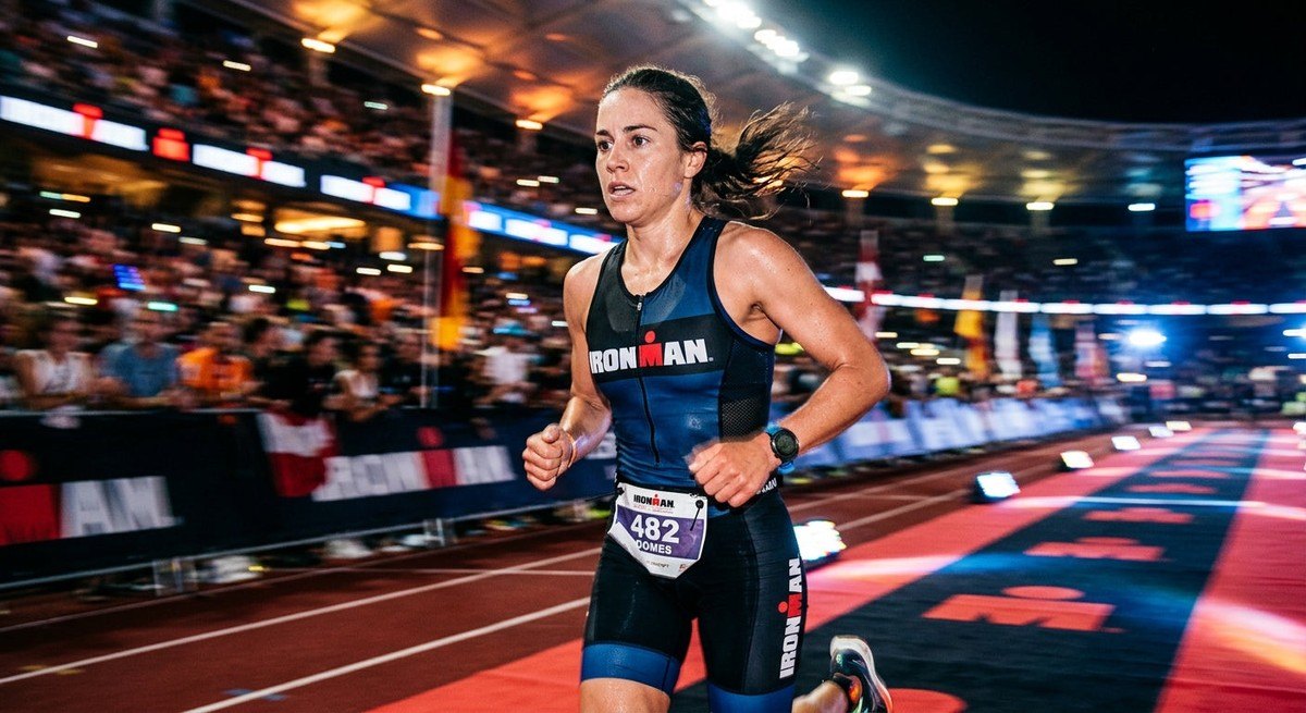 Close-up of a triathlete running with intense focus and motion blur, cinematic stadium lighting.