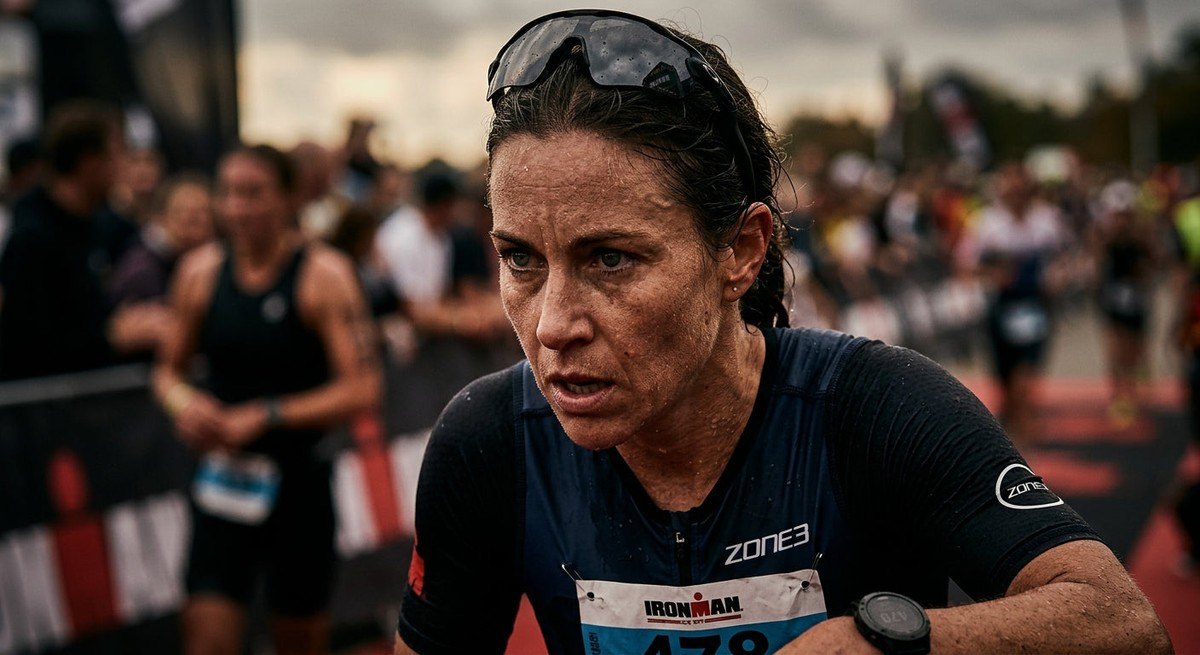 Close-up of a triathlete's face showing intense focus during a race, with fine details of sweat and texture, illuminated by moody, cinematic contrast.
