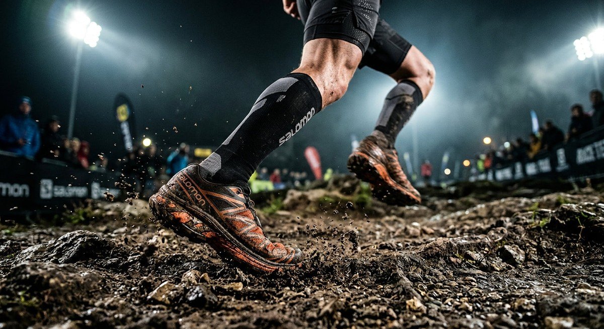 Close-up of an athlete's feet hitting a technical trail, showing realistic dirt textures and motion blur, cinematic stadium lighting style.