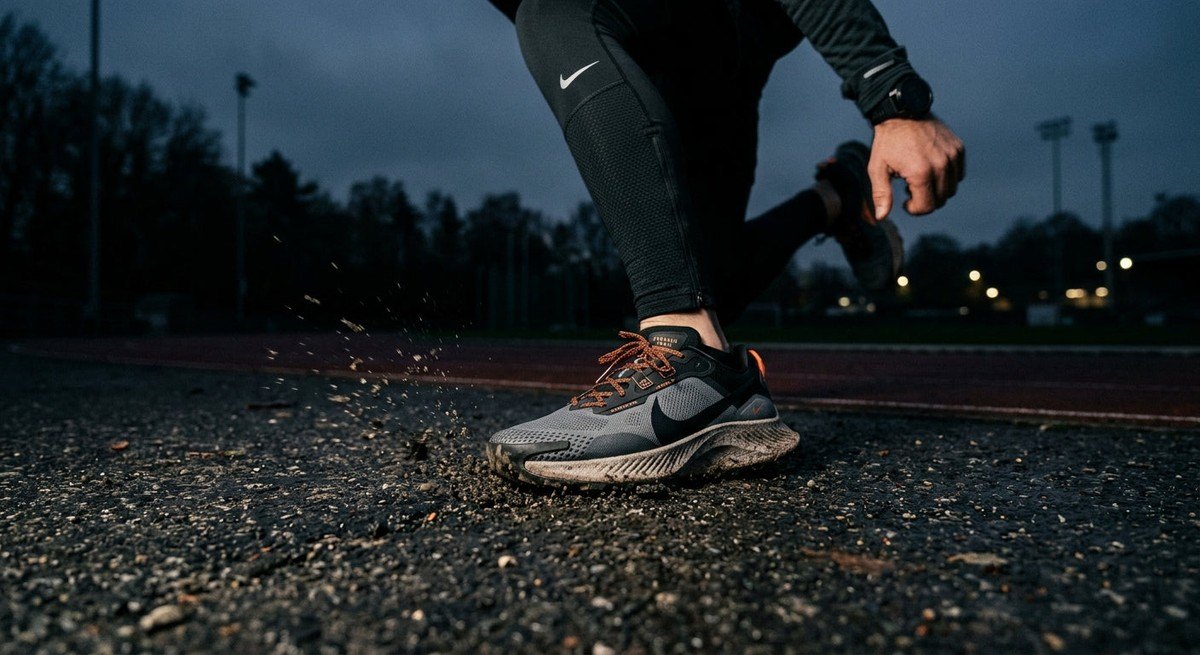 Close up of an athlete's running shoes hitting the pavement with motion blur and sharp textures, moody aesthetic.