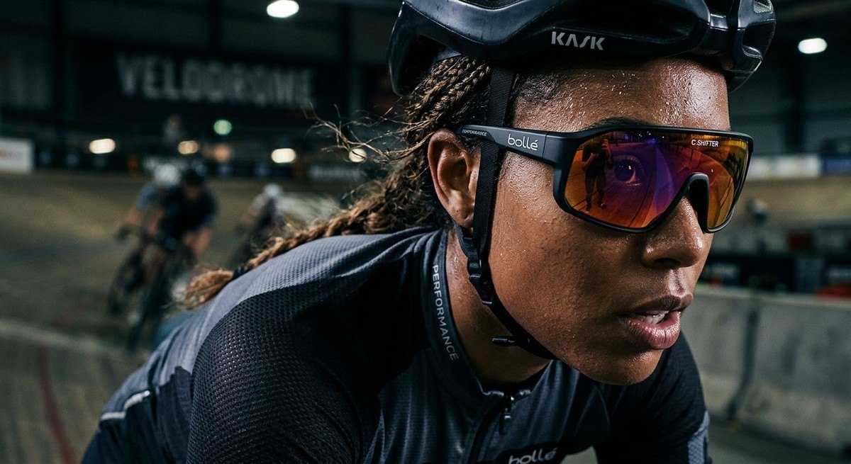 Close-up of the Bollé C-Shifter sunglasses showing the refined lens curvature and high-contrast coating textures in a moody, professional athletic setting.