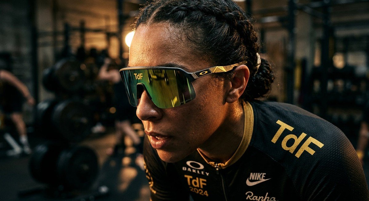 Close-up of the Oakley Sutro Lite Sweep TdF edition frame showing metallic textures and premium lens finish under moody cinematic lighting.