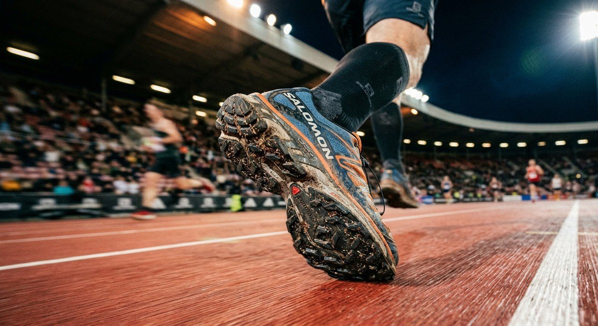 Close up of the Salomon XT-4 outsole texture and lug geometry with motion blur in a stadium setting.