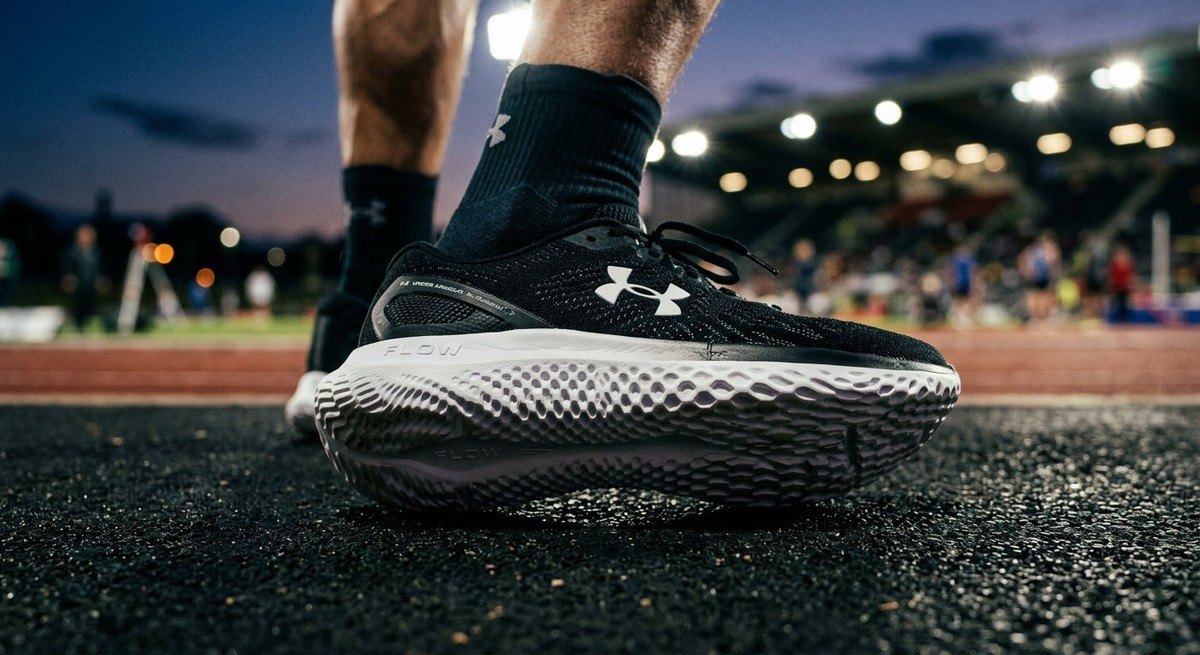 Close-up of the Under Armour Velociti SPD midsole showing the intricate Flow foam structure and technical geometry under cinematic stadium lighting.