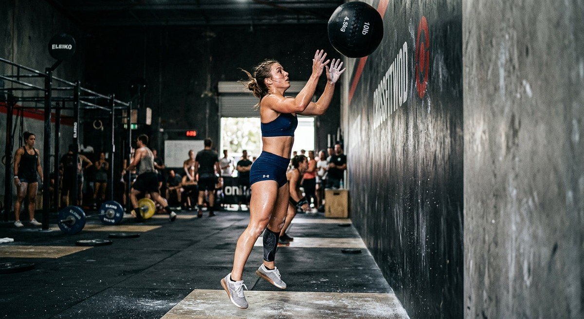 Close-up shot of a focused athlete mid-wall ball repetition, captured with high-speed photography to highlight sweat and intense muscle engagement.