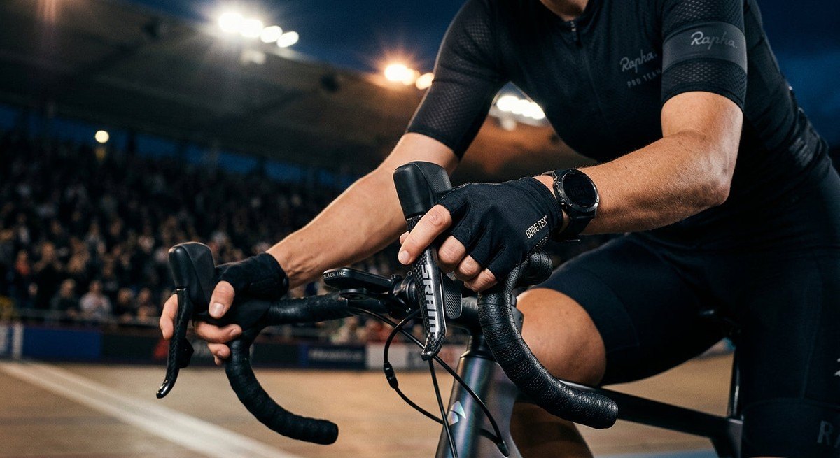Detail shot of ergonomic bike shifters on a custom road bike with a shallow depth of field and dramatic stadium lighting.