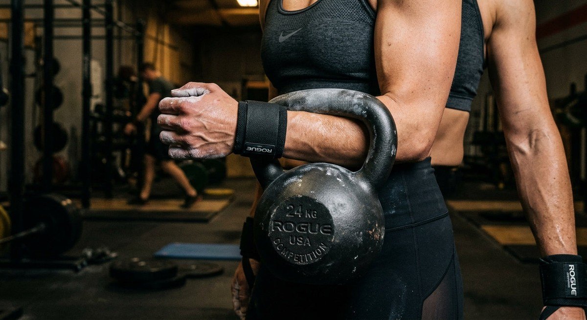 Detailed close-up of a high-grade steel competition kettlebell reflecting dramatic light, emphasising the textured grip and professional engineering.