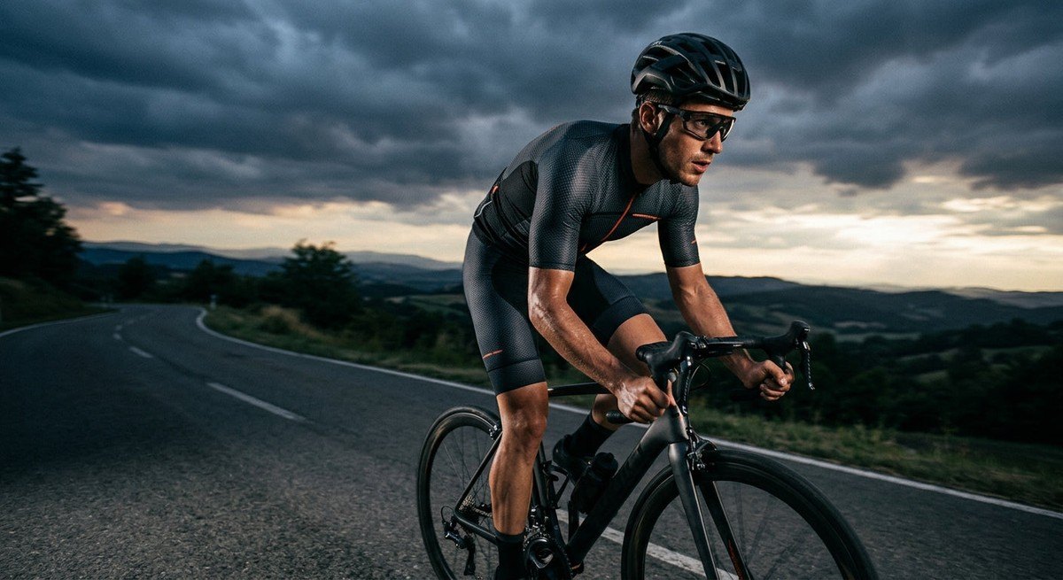 Dramatic athletic portrait of a cyclist in motion, showcasing the lightweight design of performance eyewear against a moody sky.