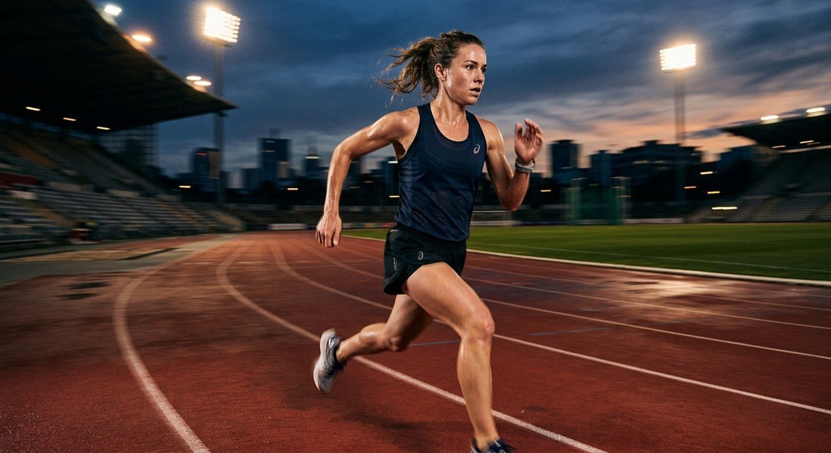 Dramatic shot of an endurance athlete training at dusk, showcasing intense focus and realistic motion blur in a stadium setting.
