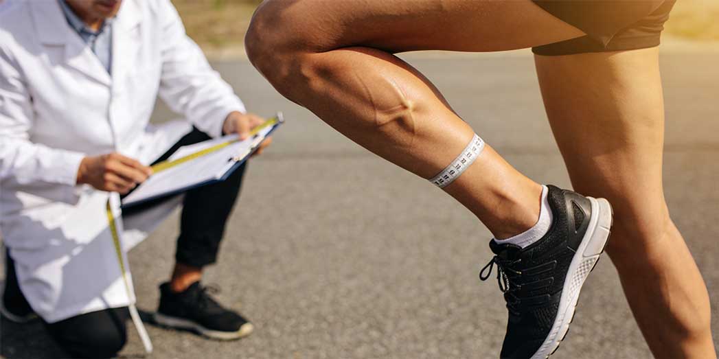 A female runner performing a one-legged hop test on pavement to check for stress fractures and bone tenderness.