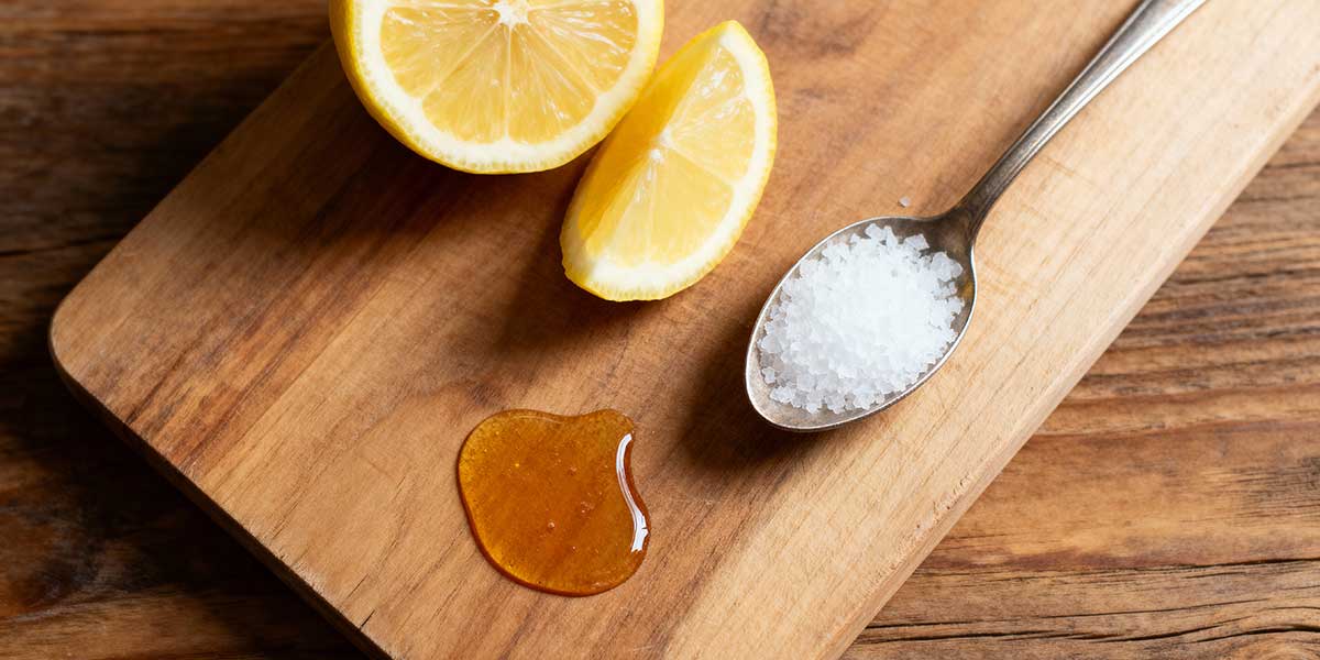 Ingredients for a homemade electrolyte drink including fresh lemon, sea salt, and honey.