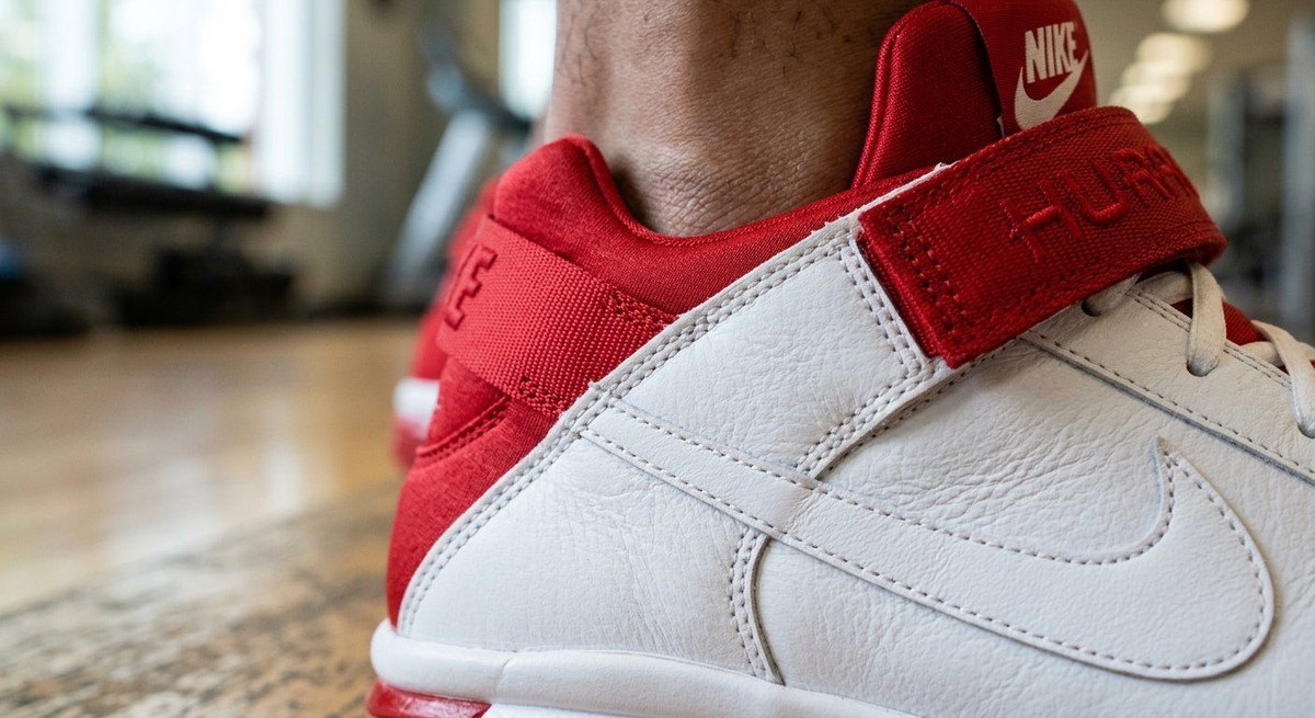 Macro close-up shot of the white leather texture and Varsity Red accents on the Nike Air Zoom Huarache 2K4 showing fine stitching details.