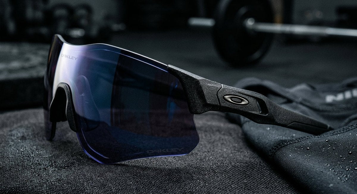 Macro detail shot of the aerodynamic lens curvature and textured frame material of the Oakley QNTM Kato in a moody, high-contrast studio setting.