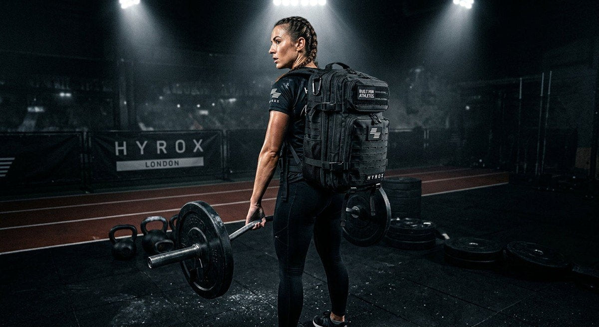 Moody, high-contrast studio photography of the Built For Athletes 35L Hyrox backpack, highlighting the durable fabric texture and tactical design elements under sharp stadium lighting.