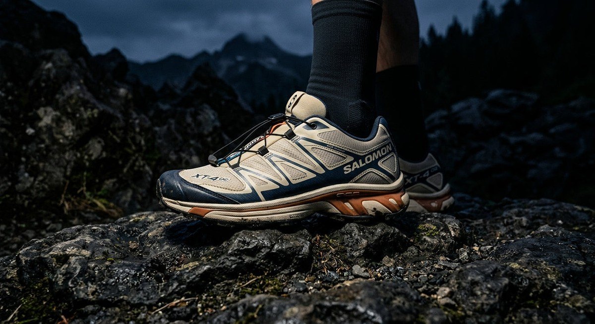 Moody side profile of the Salomon XT-4 OG on a rocky surface showing fine mesh detail and sharp contrast shadows.