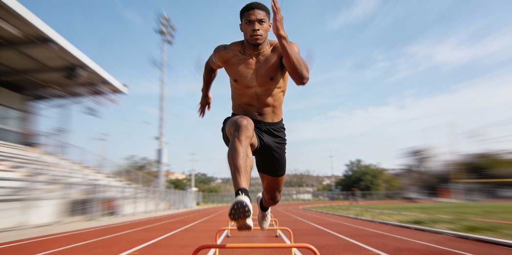 A runner performing dynamic plyometric skipping drills on an athletic track to improve tendon stiffness and form.
