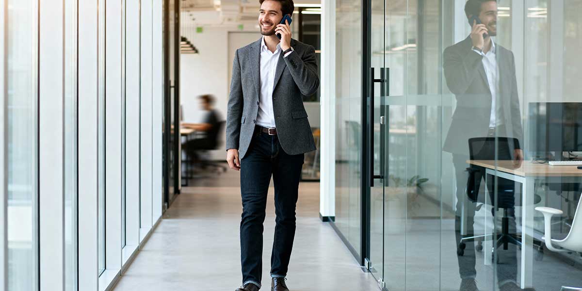 Office worker standing up and pacing while taking a business call on a mobile phone to avoid sitting.
