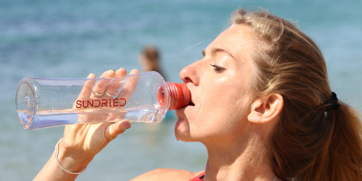 Woman drinking water on a sunny beach