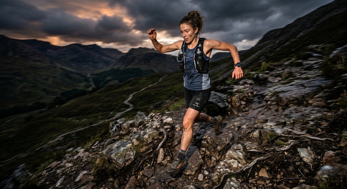 Trail runner navigating a technical descent with motion blur, highlighting athletic gear and intense, moody lighting.